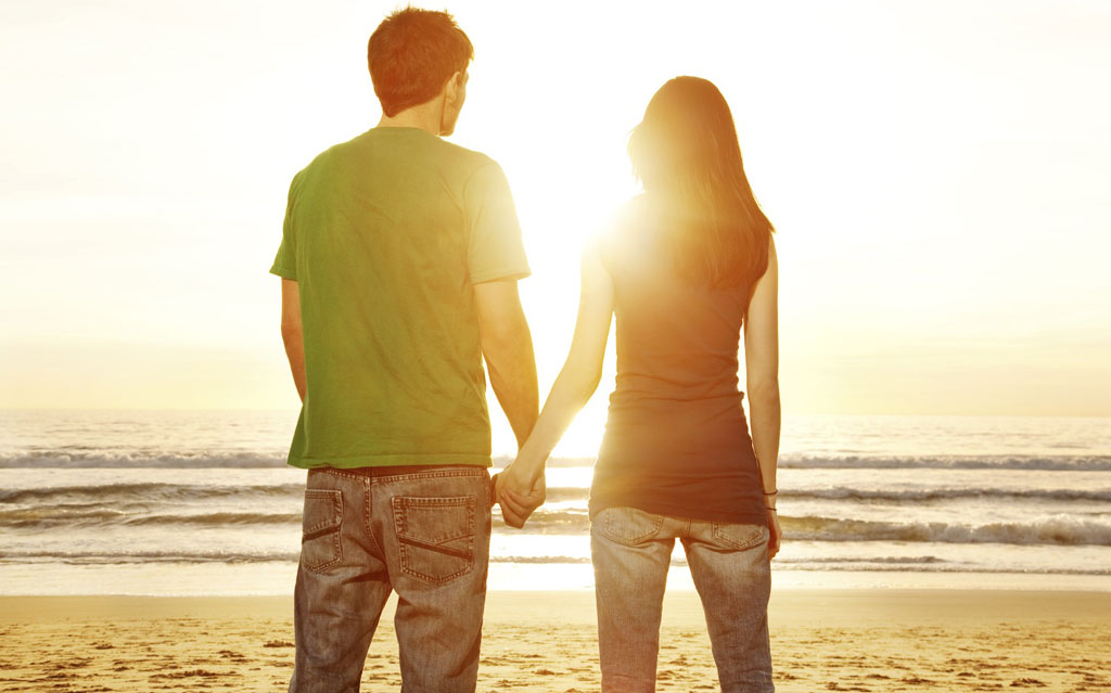Couple standing on a beach watching sunset