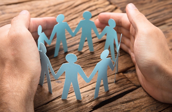 Businessman's Hands Covering Paper Team On Table